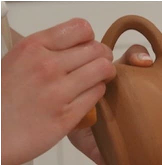 Hands shaping a mug handle